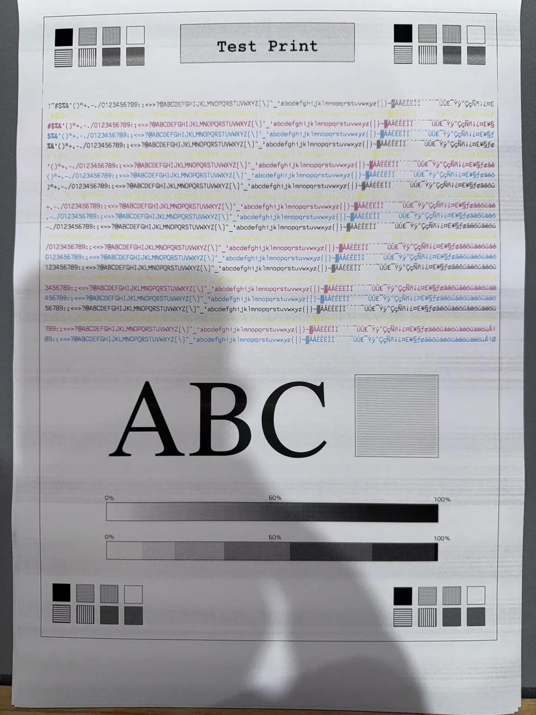 Photographed printer test page showing horizontal banding across printed text and color areas