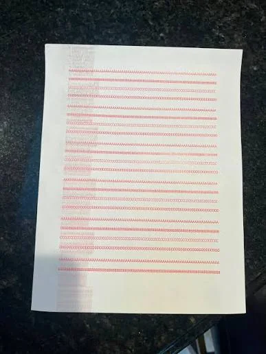 Photographed test print showing repeated streak-like marks and uneven printed output